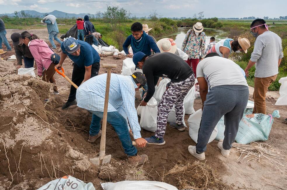Integrantes del FPDT, jóvenes normalistas y amigos del Frente llenan sacos con tierra durante la faena.