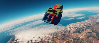 Ein Sitz schwebt über der wie aus einer Flugzeugperspektive zu sehenden Erde