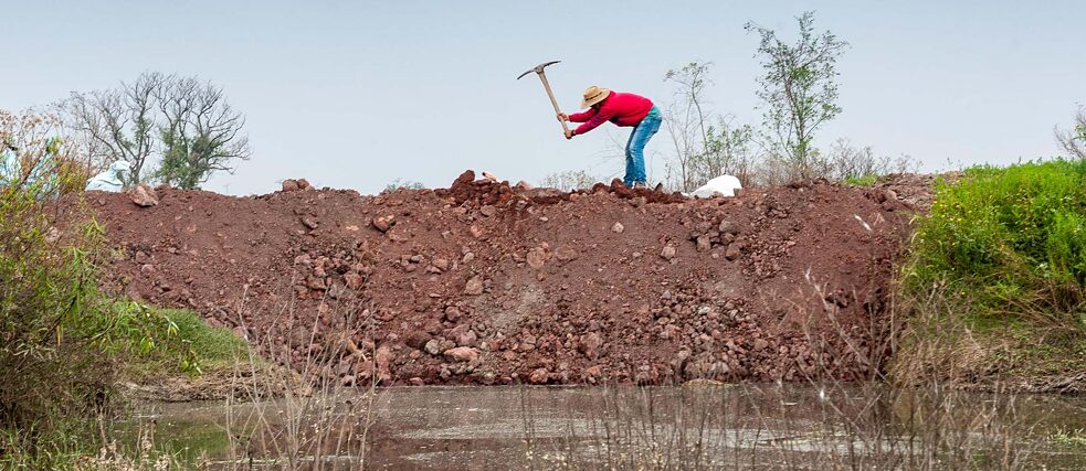 Daniel, un integrante del FPDT, pica la tierra del dique construido en la faena.