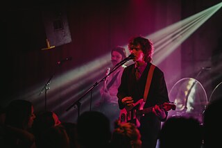 Ein junger Musiker, der ein Rockkonzert auf der Bühne gibt.