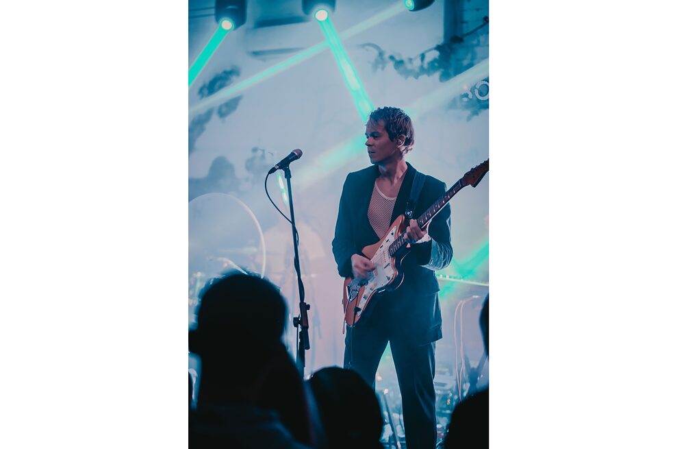 Ein junger Musiker, der ein Rockkonzert auf der Bühne gibt.