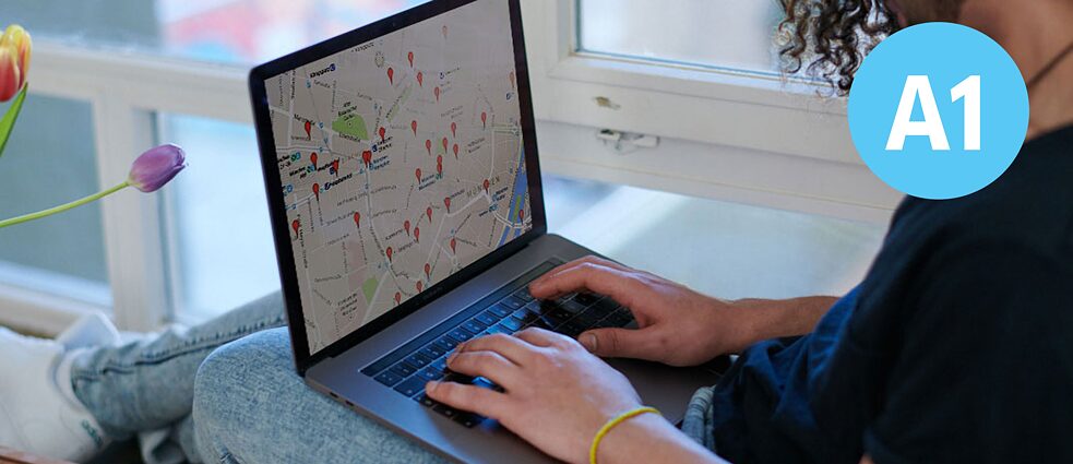 Ein junger Man sieht auf eine Karte auf seinem Laptop.