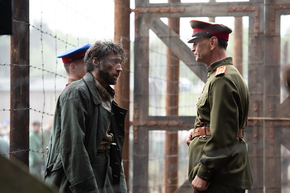 Leopold Garten (Benjamin Sadler, left) is taken prisoner by the Russians and is put under pressure by Colonel Izosimov (Ivan Gvera, right).