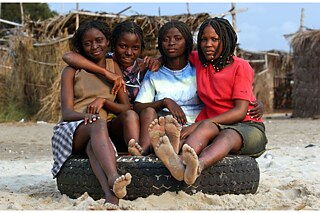 Junge Frauen in Angola auf einem Autoreifen: am Benfica Beach, 30 Autominuten außerhalb der Hauptstadt Luanda