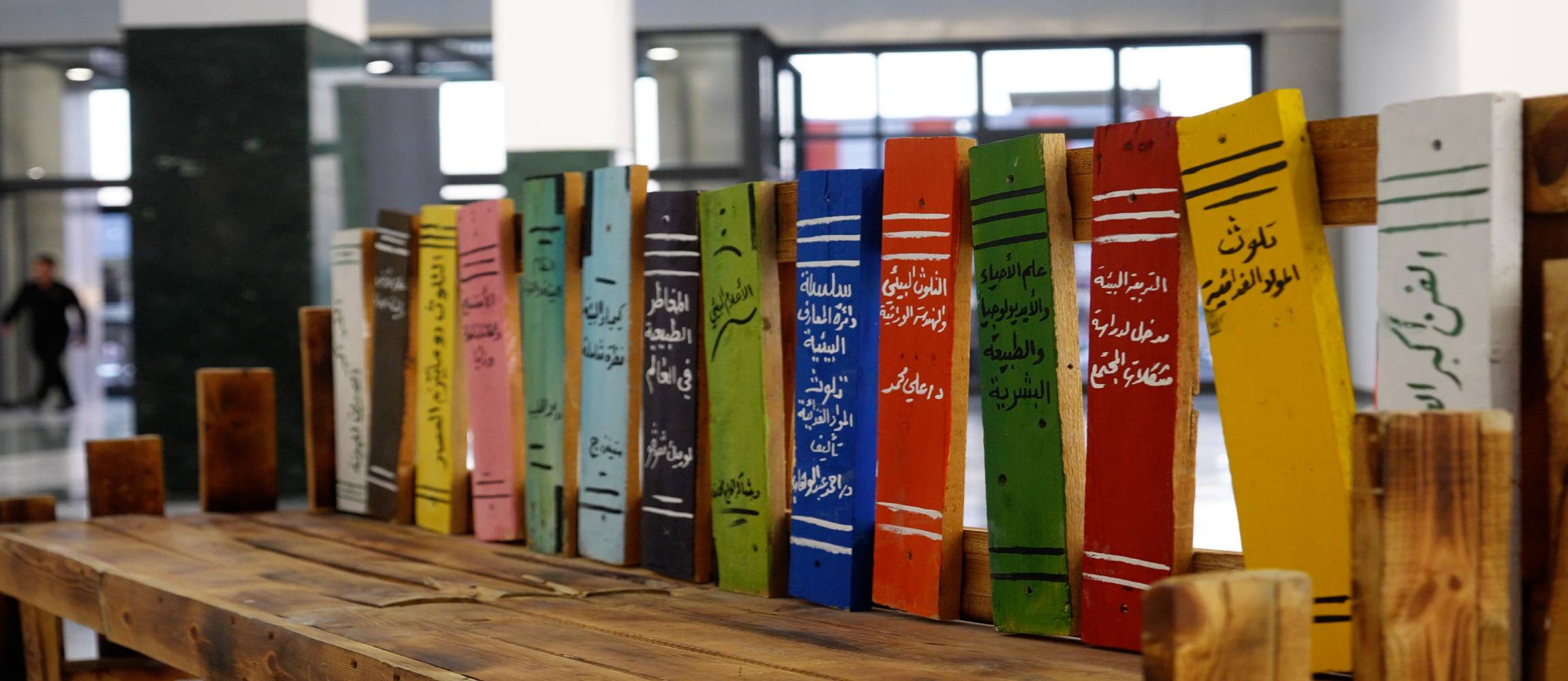  Dargestellt ist eine Holzbank mit Schrift zum Thema Umwelt im Rahmen der Ausstellung „Die Umwelt ist der größte Freund der Kunst“ in Kirkuk