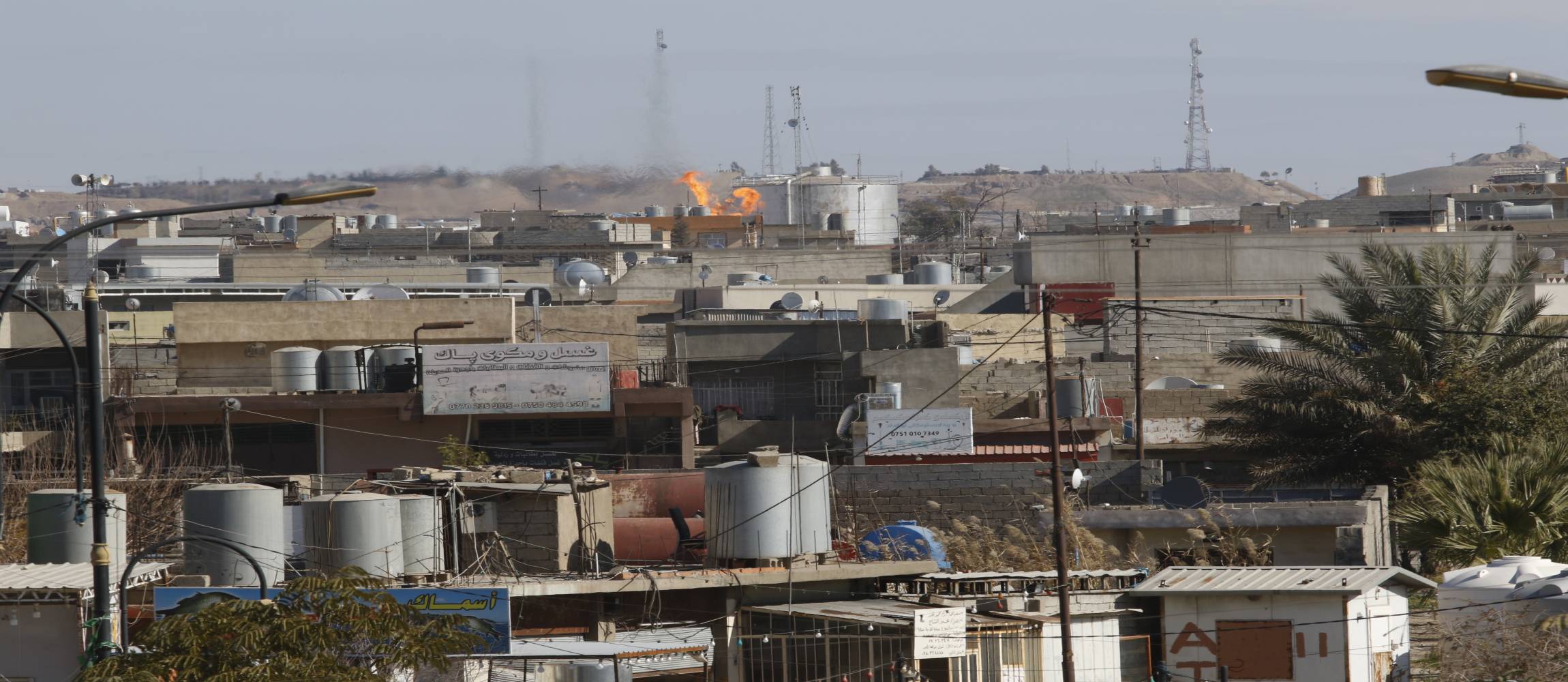 Dargestellt ist ein Wohnviertel in Kirkuk und das Feuer, das durch die Verbrennung von Erdgas entsteht.
