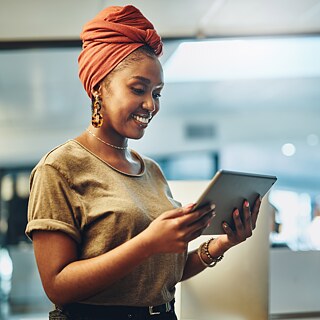 A young woman looking at a tablet, smiling.