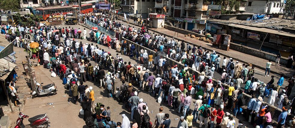 Migrant workers stand in queue in Mumbai, India, to board a bus home during a nationwide lockdown in 2020. 