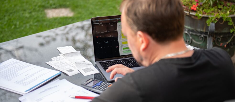 한 남성이 집에 있는 정원에 앉아 노트북으로 일하고 있다.  촬영 일자: 2021년 9월 13일.