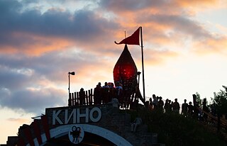 Festivalbesucher stehen auf einem alten Flugzeughangar neben einer beleuchteten Fusion-Rakete.