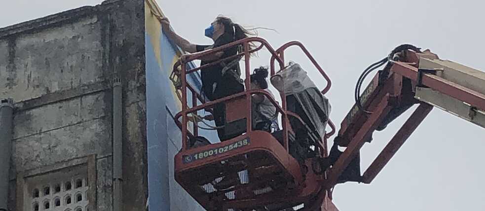 Die beiden Künstler tragen die ersten Pinselstriche auf die Wand auf.