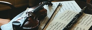 Eine Geige und eine Klarinette liegen auf Notenblättern.