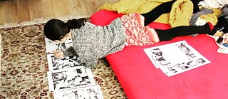 Frau liegt auf Matratze und zeichnet auf Blättern am Boden