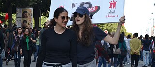 Two women at a protest for women’s rights holding up a sign: “Women’s Rights in Tunisia are irreversible“