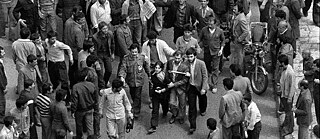 A black and white photo, a young woman is led through a crowd by several men
