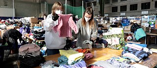 Freiwillige sortieren an einem Tisch Kleidung