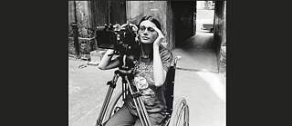 B/W photo showing a woman with a film camera