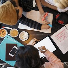 Ein Schüler sitzt an einem Tisch mit seiner Lehrerin und bearbeitet einen Text mit einem bunten Marker.