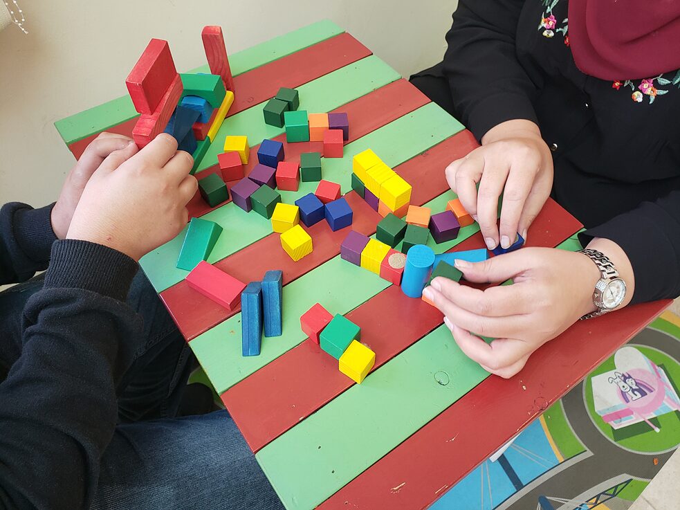 الطفل سلام يلعب مع الأخصائية النفسية والمستشارة حنان وليد لعبة "سلم وثعبان" خلال جلسة علاجية.
