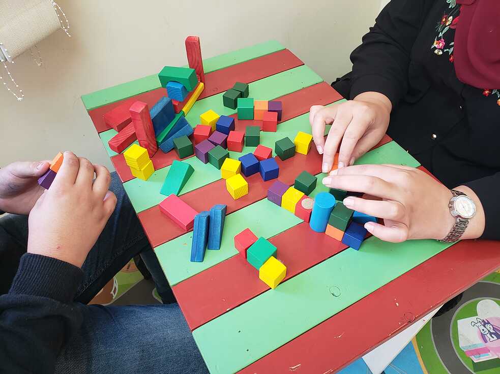 Patient Salam spielt während einer Therapiesitzung mit der Psychotherapeutin Hanan Walid das Spiel „Leiter und Schlange“.