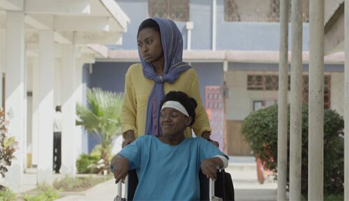 In the multi-award winning Feature Drama, T-Junction by Amil Shivji, Fatima, played by Hawa Ally, pushes Maria, Magdalena Christopher, in a wheelchair after accidentally meeting in a hospital. Cece Mlay was the Assistant Director for this 2017 production.