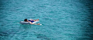 Hombre tumbado en el agua sobre un flotador