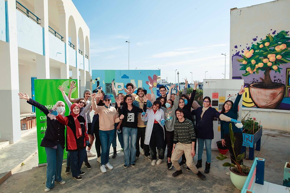 Photo de groupe avec des élèves contents dans la cour de l'école devant un mur couvert de graffitis 