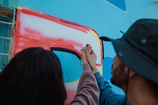 Deux mains tiennent une bombe aérosol et vaporisent sur un mur.