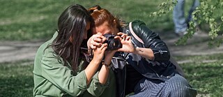 Zwei Frauen fotografieren in einem Park.