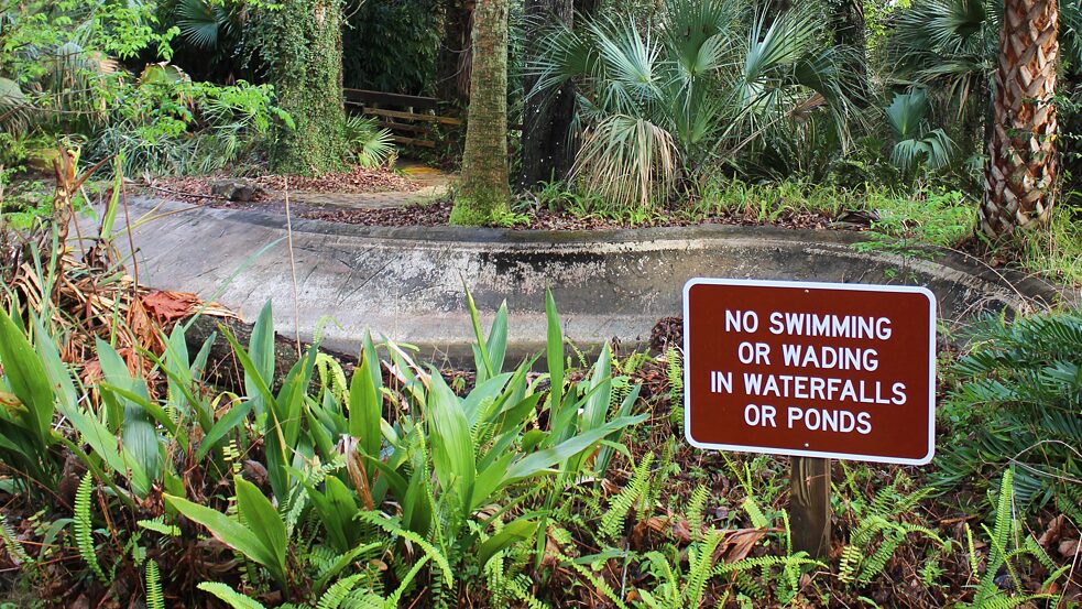 An abandoned animal enclosure at Rainbow Springs with a sign reading “no swimming or wading in waterfalls or ponds”