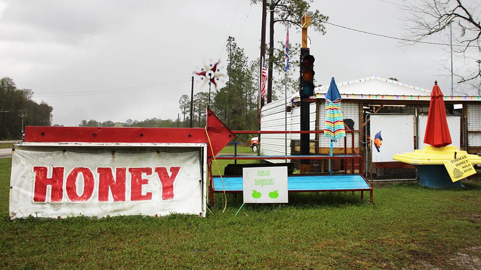 A roadside stand selling honey, nuts, and fruit