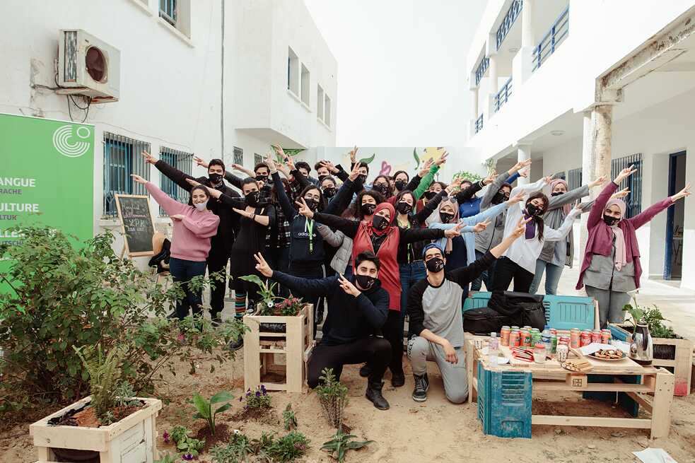 Photo de groupe avec des élèves dans la cour de l'école devant un mur couvert de graffitis