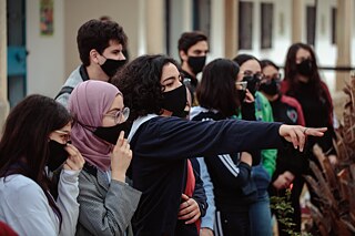 Les élèves sont regroupés ensemble et regardent dans la même direction, une fille pointe quelque chose.