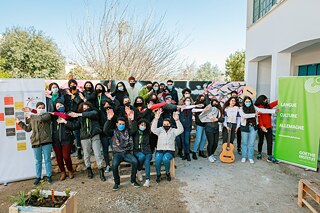 Photo de groupe avec des élèves dans la cour de l'école devant un mur couvert de graffitis