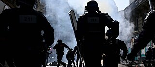 Several police officers helmeted run through a street at a demonstration