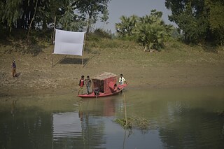   Das Workshop-Team hat ein Fotoboot gebaut, mit dem die Teilnehmer den Fluss entlang fahren können, um mit verschiedenen Fotoobjekten zu experimentieren. Die Leinwand im Hintergrund wird Teil der folgenden Ausstellung sein.
