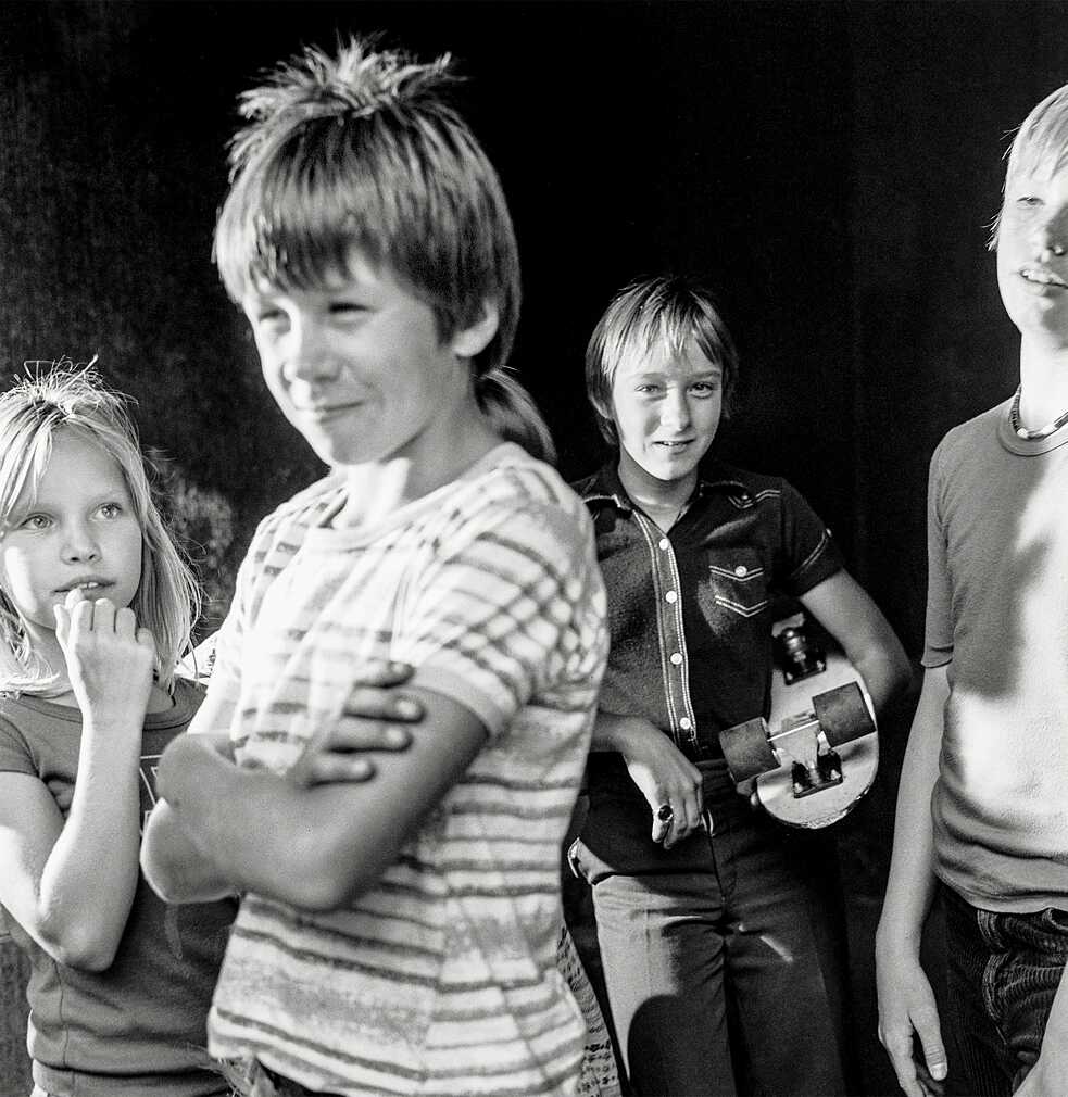 A girl and three boys standing on the street