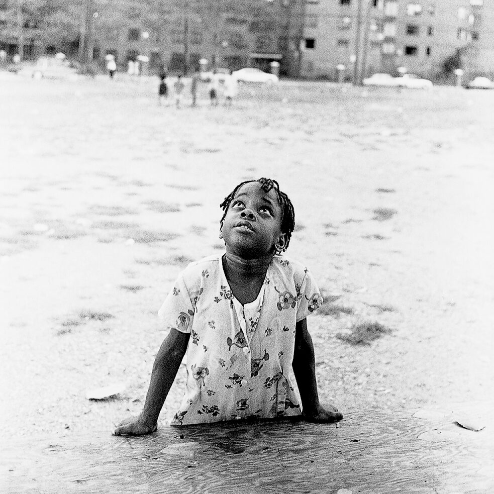 A girl sprawling on the ground in front of a building in Newark, New Jersey