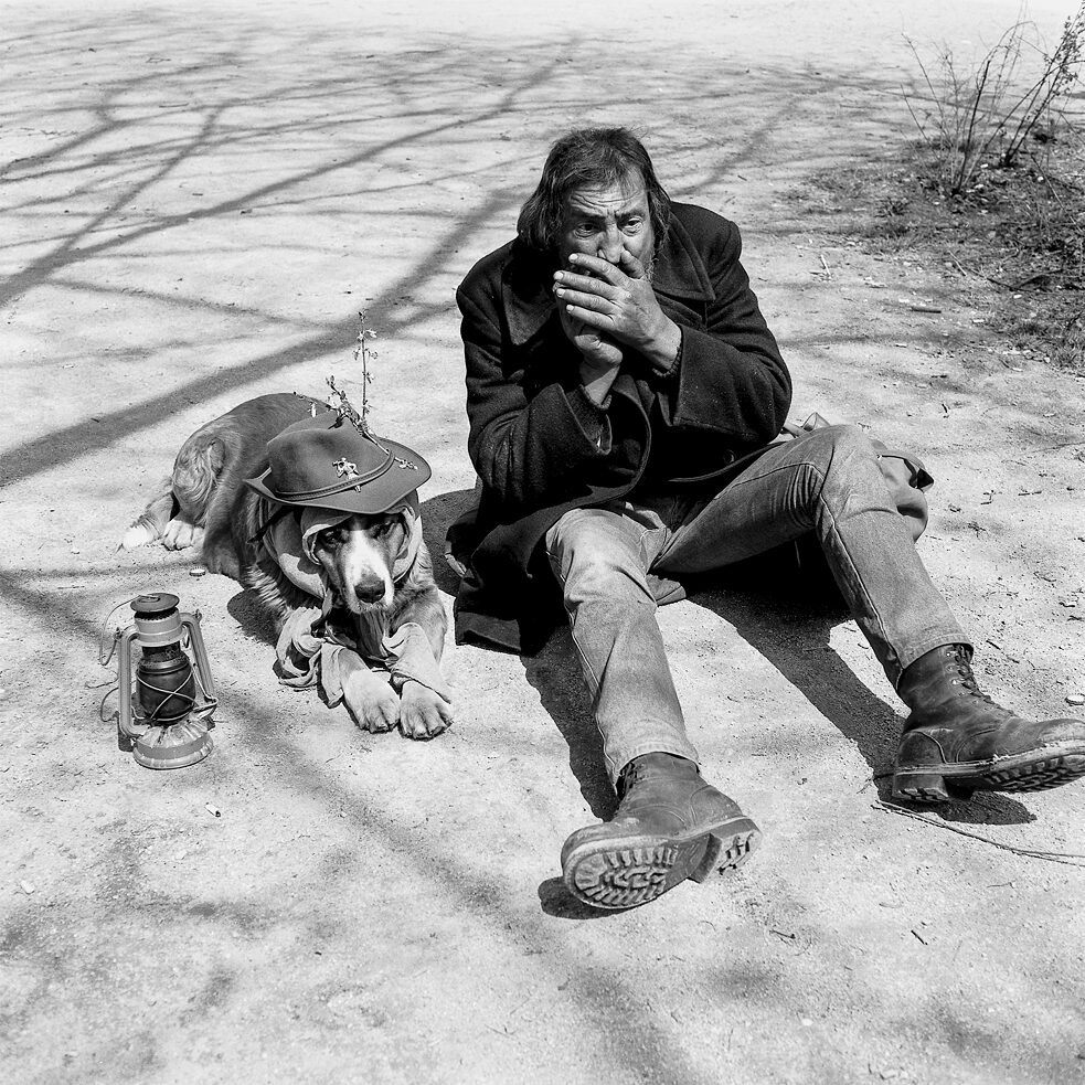 Güni, one of the homeless men that Harald profiled in Munich’s English Garden, and his dog sitting on the ground