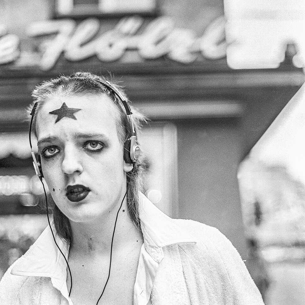 A boy with a star on his forehead walking down the street