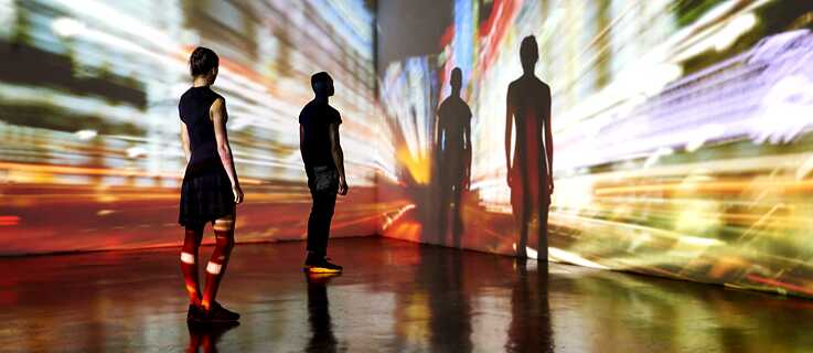 Ein Mann und eine Frau stehen in einem Ausstellungsraum vor einem Videowerk