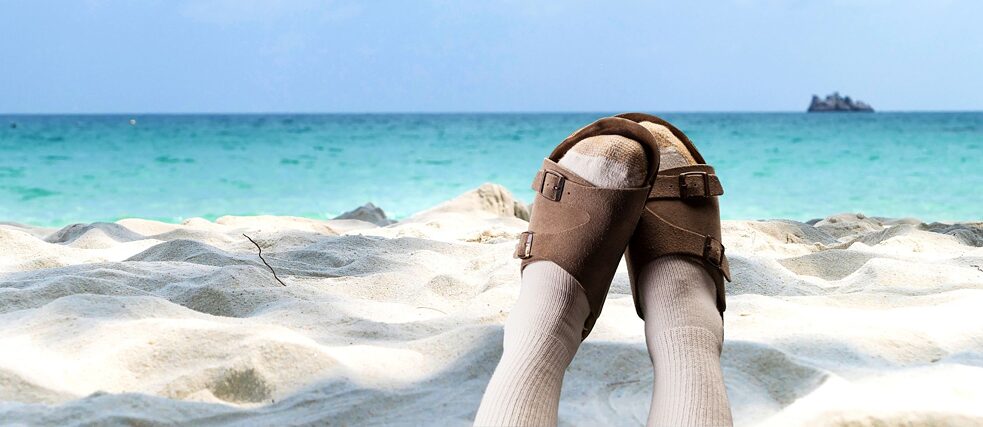 Füße mit Sandalen und Socken am Strand