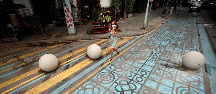 Una donna cammina per la strada a Barcellona sulla segnaletica orizzontale azzurra e gialla