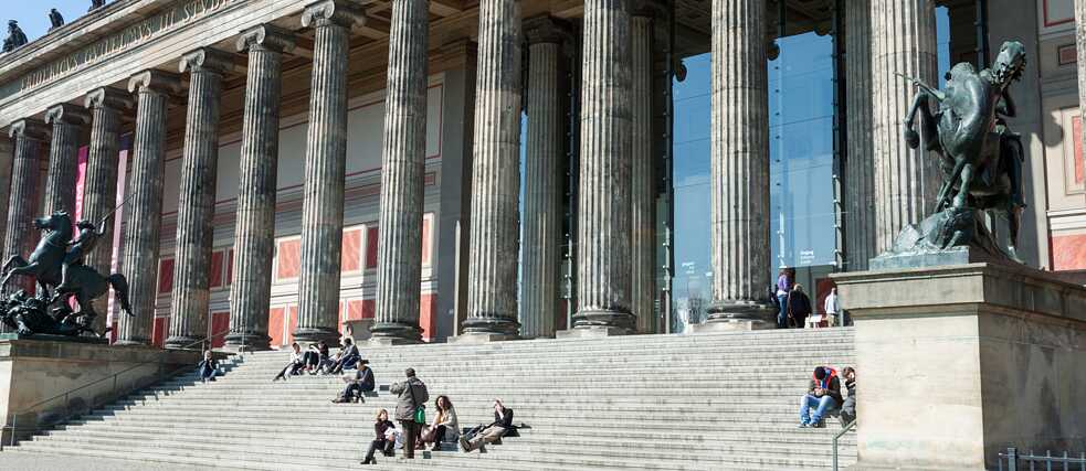 Mensen zittend op een trap voor een museum