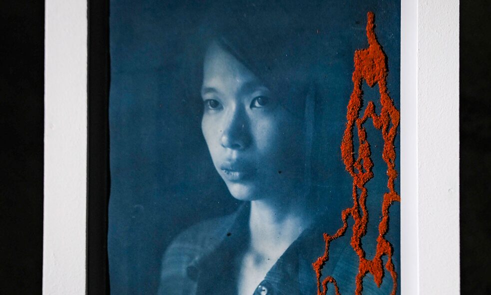 Photograph of Paddmini Chakma. The show exhibited the portraits of nine young feminists of Bangladesh, layered on top of which are maps of significant areas in Bangladesh where a sexual assault had taken place. Each of these photographs capture the indomitable spirit of the feminist who despite the toxic misogynistic culture always fight back. 