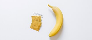 Banane liegt neben drei Kondomen