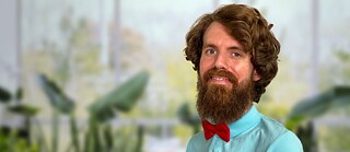 Alexander mit Pflanzen im Hintergrund und einem Lächeln