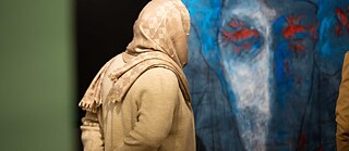 Ein Besucherin schaut auf ein ausgestelltes Gemälde der Künstlerin Hero Shekhe.