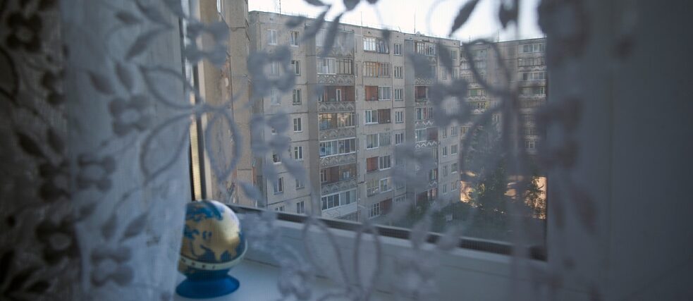 Dietro le tenda di una finestra, la vista di un complesso residenziale prefabbricato di Mosca, Russia.