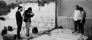 Ein Reporter und ein Kameramann filmen zwei Männer.